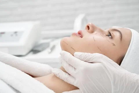 Client with markup on face visiting surgeon in clinic Stock Photos