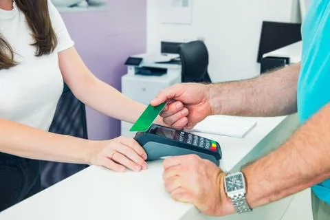 Client at the reception desk making contactless payment with nfc technology c Stock Photos