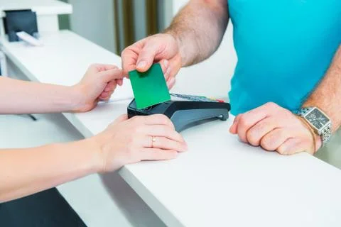 Client at the reception desk making contactless payment with nfc technology c Stock Photos