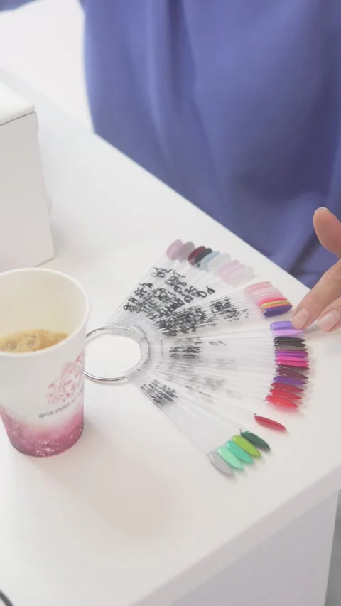 The client selects the color of nail polish on the palette during a manicure in Stock Footage 303781495