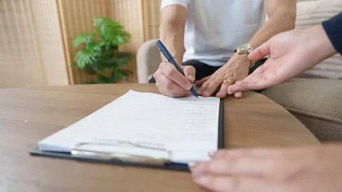 Client signing contract document on clipboard with pen during business meeting Stock Photos