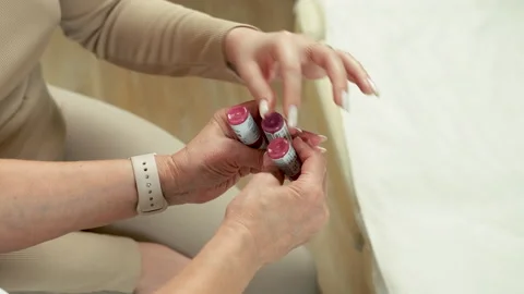 Client sits and chooses pink pigment for permanent lip makeup in a beauty salon Stock Footage 264060105
