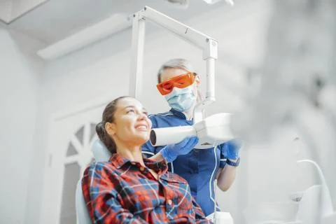 Client smiling while dentist in blue uniform holding x-ray. Stock Photos