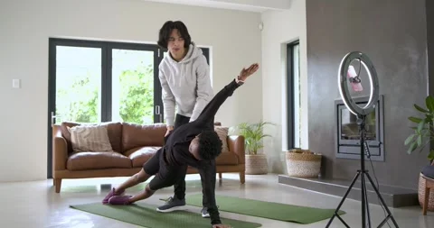 Client stepping onto mat in living room is doing side plank twist with trainer Stock Footage 343366497