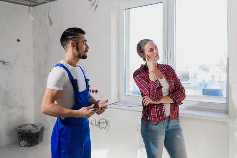 The client talks to the architect in overalls. He writes in a notebook Stock Photos