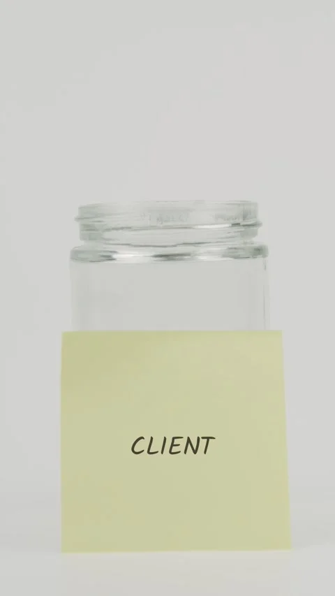 Client text or word on yellow sticky note attached to glass jar with hand Stock Footage 311692445