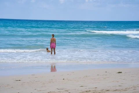 Client on th beach watching the waves, son is swimming Stock Photos