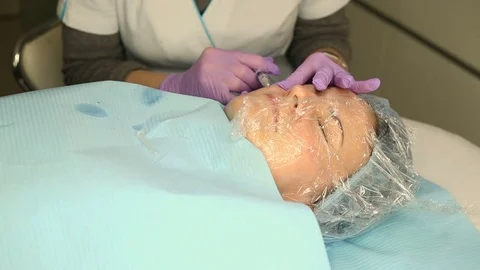 Client wearing plastic wrap on her face and having botox done Stock Footage 76187570