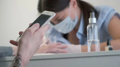 Client woman is browsing smartphone while manicure master does manicure for her. Stock Footage 145763012