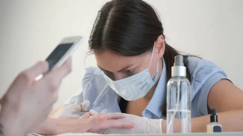 Client woman is browsing smartphone while manicure master does manicure for her. Video stock 145971471