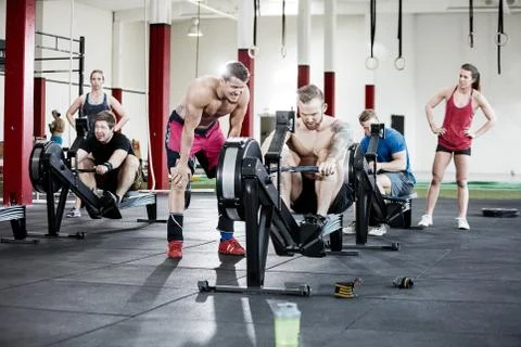 Clients Looking At Friends Using Rowing Machines Stock Photos