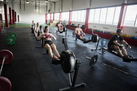 Clients Using Rowing Machines In Gym Foto stock