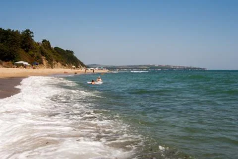 Cliff on the beach of the sea beach. Waves roll on the shore. Stock Photos