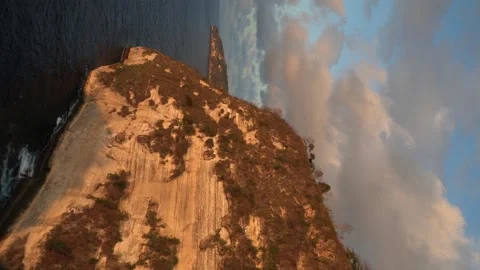 A cliff by calm waters, with a beautiful sunset in the distance Stock Footage 305437556
