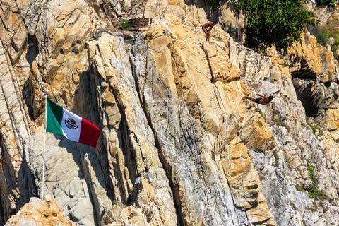 Cliff diver soaring mid-air during a high dive from the steep rocky cliffs. Stock Photos