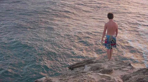 Cliff Diver - A Young Man Jumps from a Cliff into Ocean Below Stock Footage 1044915