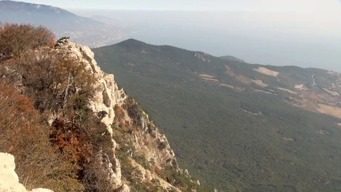 Cliff on edge of bottomless abyss. Sun illuminates mountains and sea. Stock Footage 106607930