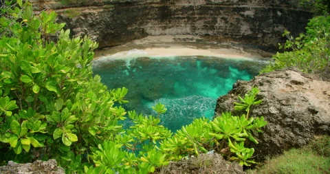 Cliff edge framing beautiful secluded bay with bright turquoise water on sandy Stock Footage 345689485