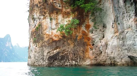 The cliff emerge on water surface, clear ripple waves Stock Footage 54070948