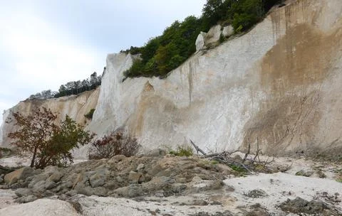 Cliff eroded by the elements with plants at the summit at risk of collapse Stock Photos