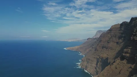A cliff falling into the blue ocean, a wall of coastal cliffs with peaks. Stock Footage 266253312