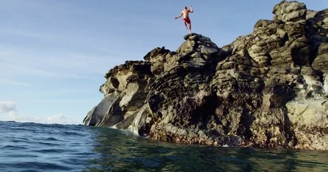 Cliff jumping back flip into blue ocean at sunset in slow motion Stock Footage 71367774