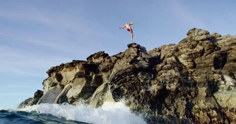 Cliff jumping back flip into blue ocean at sunset in slow motion Stock Footage 71367829