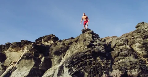 Cliff jumping backflip into blue ocean at sunset Stock Footage 71366498