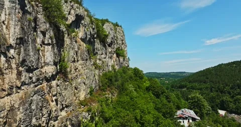 Cliff Overlooking Valley With Man Made Structures Aerial Tilt Up Zoom In Video stock 300444307