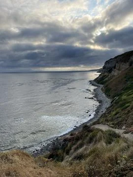Cliff View Overlooking the Pacific Ocean and Storm Clouds During Sunset Stock Photos