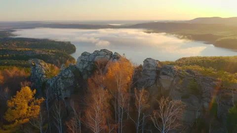 Cliffs against pond covered in mist. Fogged lake surrounded by autumn forest Stock Footage 218373897