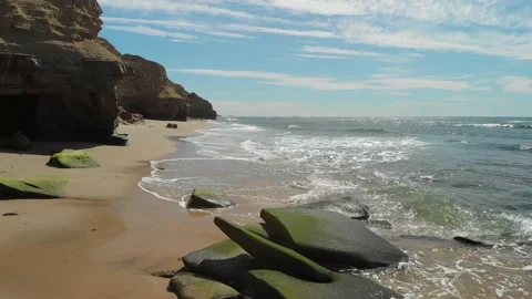 Cliffs and a beach as waves gently crash on shore Stockbeeldmateriaal 221379387