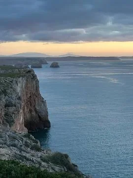 Cliffs and ocean view with cloudy sky at sunset Stock Photos