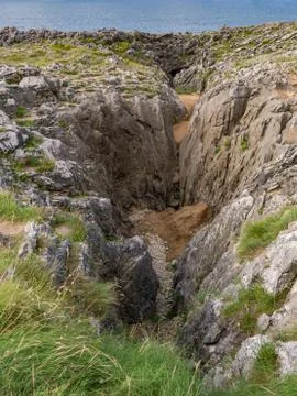 Cliffs full of rocks and vegetation by the sea Stock Photos