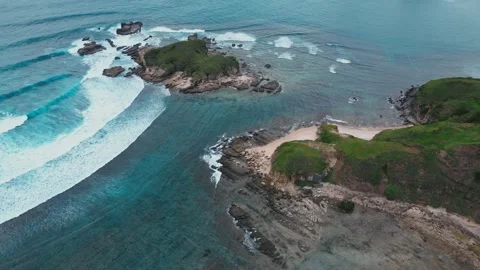 Cliffs Meet Ocean. Seaside Cliffs With Crashing Waves And Vibrant Coral Bands 動画素材 333792360