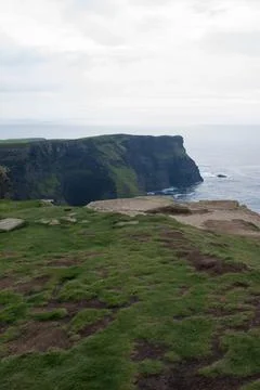 Cliffs of Moher on a cloudy day. Green fields and calm water. Ireland Stock Photos
