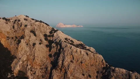 CLIFFS OF THE MOUNTAIN AT SUNSET, IN THE DISTANCE AN ISLAND IN THE OPEN SEA Vídeo Stock 188438878