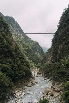 Cliffs with muddy river in valley below, with bridge going across mountains. Stock Photos