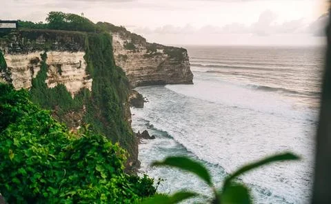 Cliffs by the ocean at sunset with waves crashing below Stock Photos
