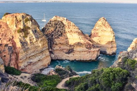 Cliffs of orange colored rocks and truqeussian waters. City of Lagos in the b Stock Photos