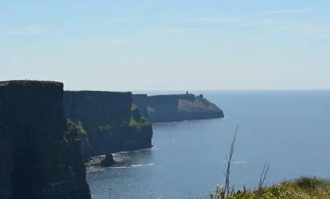 Cliffs Rise Dramatically Above the Serene Blue Sea Under a Clear Sky Stock Photos