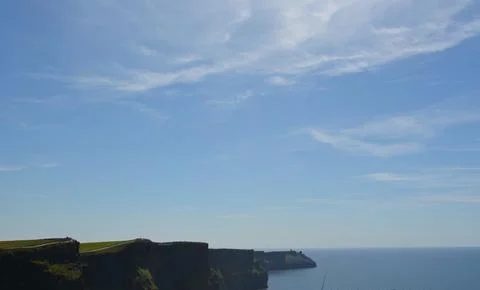Cliffs Rise Dramatically Above Tranquil Waters Beneath a Brilliant Blue Sky Foto stock