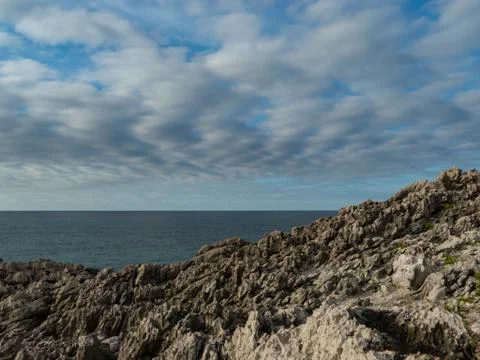 Cliffs by the sea under a blue cloudy sky Stock Photos