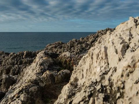 Cliffs by the sea under a blue cloudy sky Stock Photos