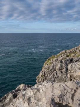 Cliffs by the sea under a blue cloudy sky Stock Photos