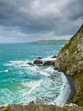 Cliffs under thunder clouds and turquoise ocean Stock Photos