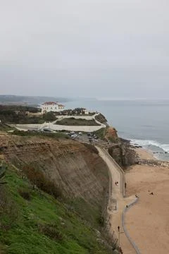 Cliffside beach curves beneath overcast sky Foto stock
