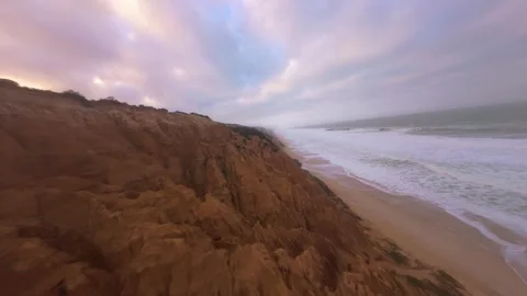 Cliffside coastal scene at dusk with waves crashing against shore Video stock 345055534
