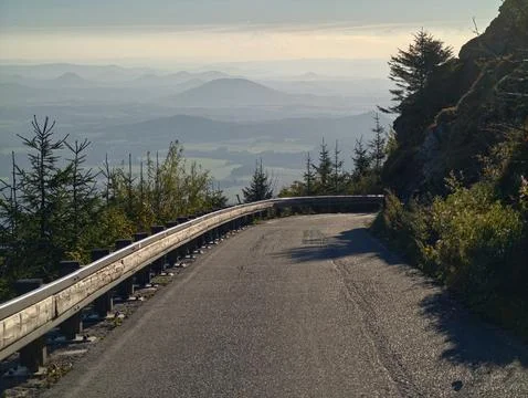 Cliffside road with panoramic views, sunlit route winding along high cliffside Stock Photos