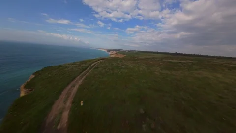 Cliffside road winds through grassy hills overlooking ocean waves Stock Footage 340224856